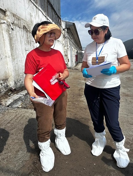 Two field researchers wearing protective shoe covers at an assessment site.