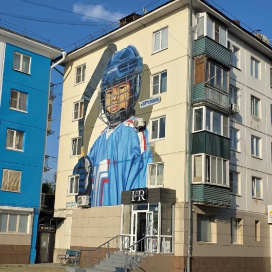 Mural of an ice hockey player on the side of an apartment building in Oskemen.
