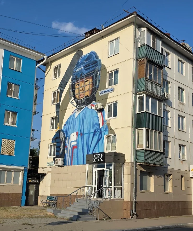 Mural of an ice hockey player on the side of an apartment building in Oskemen.