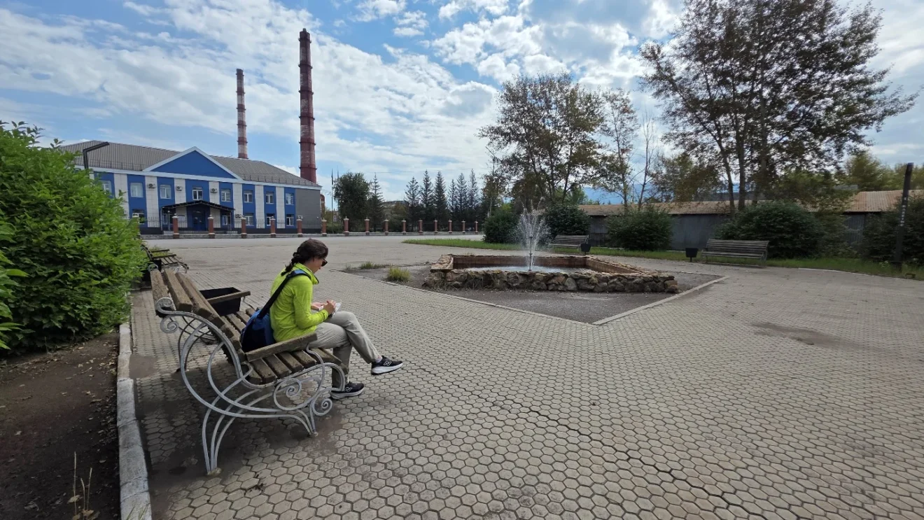 Park and fountain in front of the zinc smelter in Ridder, with industrial chimneys behind.